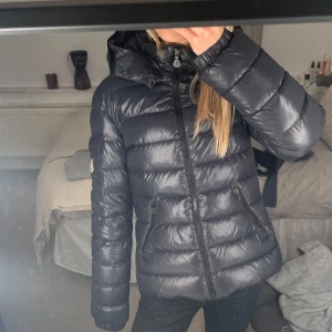 Moncler bady  - Säljer en mörkblå dunjacka från Moncler i modellen bady. Jackan är köpt för 2 år sedan, men är sparsamt använd. Det är den största storleken i barnstorlek. Den är supersnygg och varm. Vill även tillägga att tvättlappen sitter löst. Kommer bara att sälja jackan om jag får ett bra pris för den.