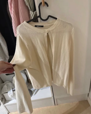 Krämvit kofta från Gina Tricot - Säljer en krämvit kofta från Gina Tricot med rund halsringning och en enkel knapp framtill. Pris kan diskuteras! 