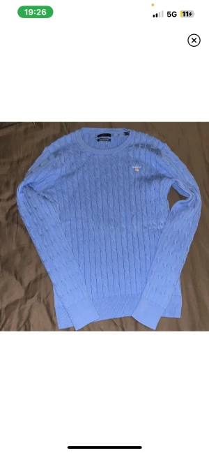  Gant tröja  - Blå kabelstickad tröja från GANT med rund hals och diskret logga broderad på bröstet. Tröjan har långärmad passform och ribbade muddar vid ärmslut och nederkant.Finns ej prislapp, togs bort vid öppning. Varan är aldrig använd säljs då min brorsa fick den i present men passad inte han. Storlek är M fast ganska säker på att det passar S passformen är tajt. Normal pris är 1600kr säljs för 499 eftersom jag inte ser att den är värd 1600 i mina ögon. 