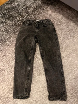 Svarta jeans från Grunt straight fit - Säljer ett par svarta jeans från Grunt med tvättad look och klassisk femficksdesign. Modellen har rak passform och normal midja, perfekt för dig som gillar en enkel och clean stil. Materialet är slitstarkt denim och färgen är mörkgrå/svart.