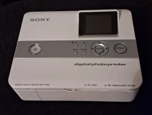 Sony Digital Photo Printer DPP-FP60 - Sony DPP-FP60 digital fotoprinter med LCD-skärm, SD-kort och Memory Stick PRO-stöd. Komplett med tillbehör, manual och installationsskiva. Enheten och tillbehören ser ut att vara i mycket gott skick, utan synligt slitage eller defekter.
