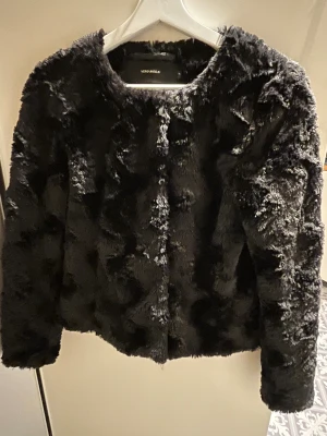 Svart pälsjacka från Vero Moda XS - Säljer en svart pälsjacka från Vero Moda i storlek XS. Jackan har en fluffig och mjuk yta med rund hals, tryck knappar och långa ärmar. Perfekt för dig som vill ha en cool och trendig look med extra attityd. 
