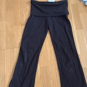 Svarta och grå yoga pants från Gina Tricot Young  - Två par yogapants i svart och ljusgrått, båda med bred, vikt midja och långa, raka ben. Byxorna är tillverkade i mjukt och stretchigt material som är skönt mot huden. Perfekta för chill eller träning, med loose passform och enkel design.