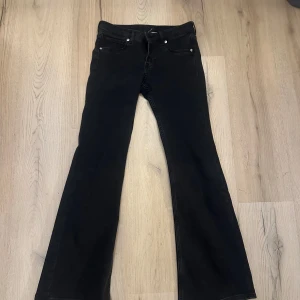 Svarta bootcut jeans från H&M - Svarta jeans från Divided i klassisk femficksmodell med bootcut-ben. Jeansen är långmidjade och är tillverkade i ett stretchigt material för skön passform. Jeansen är små i storlek och passar mig som normalt har 34 / 36. Byxorna är helt nya och säljs då de var för korta för mig som är 172.