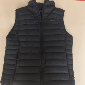 Mörkblå dunväst från Patagonia - Patagonia dunväst-mörkblå storlek M Snygg och klassisk dunväst från Patagonia i mörkblått. Superlätt, varm och riktigt skön – perfekt till höst eller lager på lager. Använd väldigt lite, skick 9/10. Inga fläckar eller skador. Nypris 2400