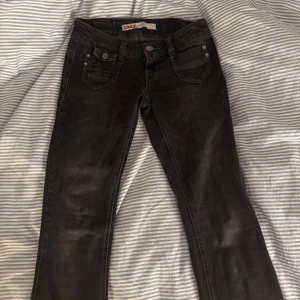 Svarta jeans från ONLY med raka ben - Svarta jeans från ONLY med raka ben och klassiska femficksdetaljer. Jeansen har snygga sömmar, silverfärgade knappar och en diskret tvättad look. Perfekta för dig som gillar en enkel och stilren vibe. Storlek 27