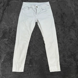 Vita byxor från Dondup - Snygga vita byxor från Dondup i storlek 31. De har klassisk femficksdesign, raka ben och normal passform. Byxorna är tillverkade i ett mjukt bomullsmaterial och har diskreta detaljer med metallnitar och logotyp på bakfickan.