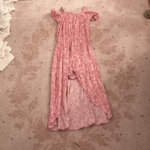 Rosa blommig långklänning Lindex Kids ✨💞✨ - Supersöt rosa långklänning från Lindex Kids med blommigt mönster, offshoulder och smock upptill. Klänningen har volangärmar och en luftig, flowy passform – perfekt för varma dagar. Tillverkad i mjuk bomull som känns skön mot huden. Känns som en dröm! ✨🫶🏻✨