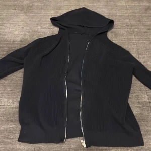 Svart hoodie med dragkedja - Svart/mörkblå hoodie med dragkedja framtill. Tröjan har huva och långa ärmar, perfekt för en chill och avslappnad stil. Passar bra till jeans. Enkel och stilren design utan synliga loggor. PRIS 199kr        SKICK 9/10