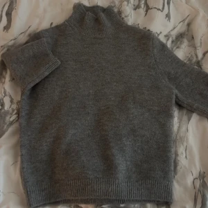 Grå polotröja från Zara - Mysig grå polotröja från Zara i stickad ullmix. Tröjan har en hög krage och ribbade muddar vid ärmslut och nederkant. Nästan helt ny, endast andvänd en gång 