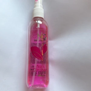 NG Nail Cleaner rosa sprayflaska - En rosa genomskinlig sprayflaska med NG Nail Cleaner, perfekt för att rengöra naglar. Flaskan rymmer 100 ml och har ett vitt spraymunstycke. Snygg design med rosa och guldiga detaljer på etiketten.
