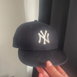 New Era New York Yankees keps marinblå - Snygg marinblå New York Yankees keps från New Era med klassisk vit NY-logga framtill och MLB-logga bak. Kepsen har rak skärm och broderad New Era-logga på sidan. Perfekt för dig som vill ha en sportig och stilren look. Pris kan diskuteras vid snabb affär