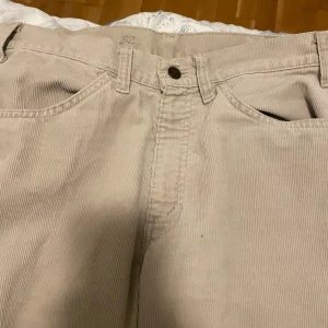 Beiga manchesterbyxor baggy - Säljer ett par snygga beiga manchesterbyxor med klassisk passform. Byxorna har fem fickor, bälteshällor och stängs med knapp och dragkedja. Perfekta för dig som gillar retrovibbar och vill ha ett coolt tillskott i garderoben.