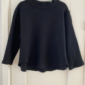 Svart ulltröja från Eileen Fisher - Svart, loose-fit tröja från Eileen Fisher i mjuk ull. Tröjan har en enkel design med rundad hals och långärmade, något vida ärmar. Materialet är italiensk ull som känns riktigt skönt mot huden. Perfekt för dig som gillar minimalistisk och chill stil. Mått  Över bröstet: ca 58 cm  Längd från axeln och ner: ca 56 cm   100% ull   Kommer från ett djur och rökfritt hem. 