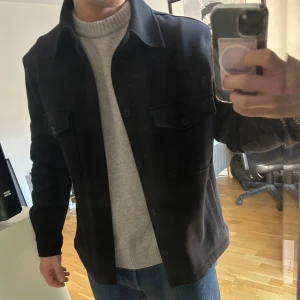 Svart overshirt från Zara - Stilren svart overshirt från Zara i. Perfekt lager-på-lager-plagg med normal passform. Otroligt bra skick men har inte kommit till användning tyvärr. Storlek M.