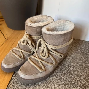 Beige Inuikii vinter skor i mocka - Säljer ett par beige Inuikii vinter skor med mjuk fårullsfoder, ovandel i mocka och skinn samt grova snören som detalj. Köpta till förra vintern och är i nästan ny skick. Skorna håller värmen jätte bra och dem är impregnerade! Säljer enbart för att jag fått ett par nya🥰 inga defekter