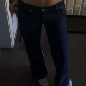 Mörkblå lowwasit loose jeans från Nelly - Snygga mörkblå jeans från Nelly med klassisk femficksdesign och bootcut passform. Jeansen har låg midja och är tillverkade i ett stretchigt denimtyg som sitter skönt. Perfekta för dig som gillar en tidlös och trendig look.