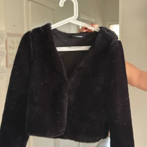 Svart pälsjacka från Gina tricot  - Mysig svart pälsjacka från Gina tricot med croppad passform och lång ärm. Helt oanvänd det är spegeln som är smutsig inte jackan ! 