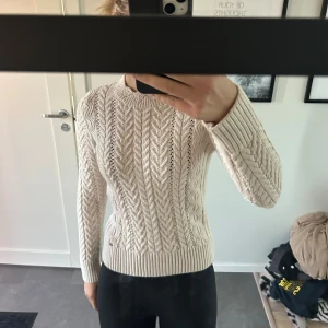 Beige stickad tröja - Säljer en beige stickad tröja från SUPERDRYSARTORIAL med snyggt flätmönster och ribbade muddar. Bra skick då den inte kommit till användning.