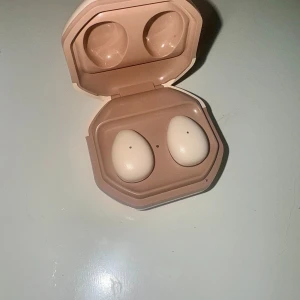 MY001 Mini Wireless Earbuds - Snygga trådlösa hörlurar i beige med laddningsetui. Bluetooth 5.3+ EDR för stabil anslutning, mikrofon för samtal och musiklyssning. Levereras med laddkabel och originalförpackning. Ser ut att vara i nyskick utan synligt slitage. Kartongen är lite fläckig, inget som påverkar hörlurarnas funktion.