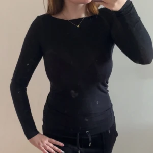 Svart Intimissimi tröja - Säljer en svart långärmad tröja med tight passform. Enkel och stilren design som sitter snyggt mot kroppen. Perfekt att matcha med jeans eller kjol för en clean look.