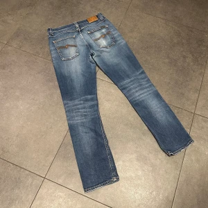 Nudie Jeans Grim Tim - Snygga blå jeans från Nudie Jeans med klassisk femficksdesign och cool tvätt.                    Modellen är Grim Tim.