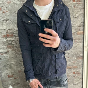 Woolrich Field Jacket - Bra skick, generellt använd och en liten skada på armen, be om bild. Storlek S passar dig som är mellan 175-180cm ungefär. Nypris ca 3000kr. Modellen är 185 cm, 79 kg. Passar bra till regn och vind. Skriv för mer information!🤝