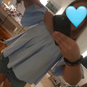 Ljusblå offshoulder blus med vida ärmar - Säljer en ljusblå blus med offshoulder-modell och vida, korta ärmar. Toppen har en lös passform och är gjord i ett tunt bomullstyg som känns luftigt och skönt. Perfekt för varma dagar när du vill ha en chill och trendig look. Passar flera storlekar. 