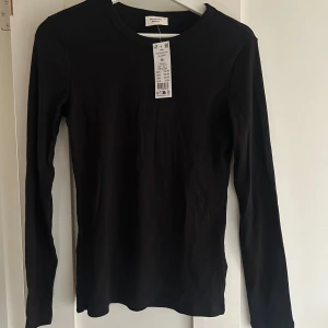 Svart långärmad topp från Gina Tricot - Säljer en svart långärmad topp från Gina Tricot i storlek M. Perfekt basplagg för alla tillfällen, med en enkel och stilren design. Toppen är i nyskick och har en bekväm passform. Perfekt för lager-på-lager eller att bära som den är.