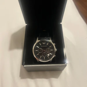 Emporio armani klocka AR2447 - Hej jag säljer min armani klocka eftersom den inte längre kommer till användning. Det är en AR2447 43mm modell som är i svart äkta läder. En mycket elegant och tidlös klocka. Nypris på klockan är runt 3000kr mitt pris är 1800 kr. 