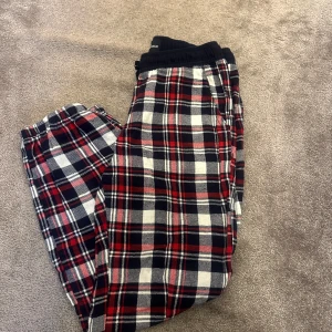 Rutig byxa från Hampton Republic - Säljer ett par mysiga rutiga byxor från Hampton Republic i storlek 146/152. Byxorna har ett klassiskt rött, svart och vitt rutmönster och är perfekta för en avslappnad dag hemma. De har en elastisk midja för extra komfort. Perfekta för höst- och vintermys!