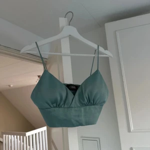 Grön linnetopp från Gina Tricot - Snygg grön linnetopp från Gina Tricot i en härlig nyans. Toppen har smala axelband och en enkel design som passar perfekt till sommaren. Den är i bra skick och redo för nya äventyr. Perfekt för en dag på stan eller en avslappnad kväll med vänner.