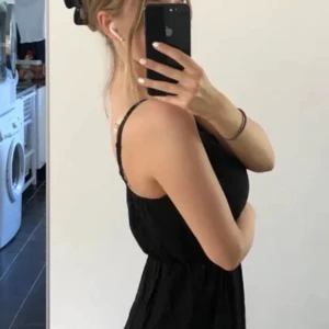 Svart ärmlös klänning - Säljer en stilren svart klänning som är perfekt för sommaren. Den är ärmlös med smala axelband och har en bekväm passform. Klänningen är enkel men elegant, vilket gör den idealisk för både vardag och festliga tillfällen.