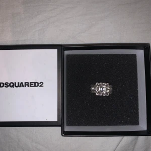Dsquared Ring  - En ring från Dsquared som är köpt från NK i Göteborg, Knappt använd.  Negativt: En av kristallerna har ramlat av på undersidan av ringen, men syns ej när man har på sig den se (bild 2)  Skriv om ni undrar något 🙃  Köptes för 1299kr Säljes för 700kr