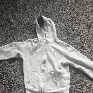 Ralph lauren zip hoodie  - Det här är en grå Ralph lauren zip med luva. Den är storlek xl i barnstolek så alltså 14-16 år. Jag säljer den för att jag har växt ur den. Nypris 1100 kr