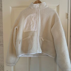 Vit beige jacka från Nelly - En vit beige lurvig jacka från nelly, sparsamt använd. Den är i storlek 46 men jag skulle säga att den sitter som en L