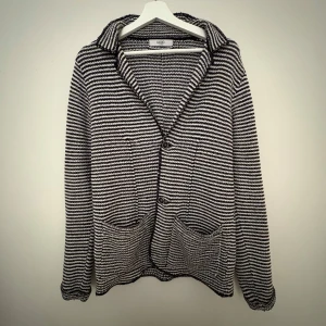 Randig kofta från Uld - Snygg randig stickad kofta i marinblå/svart och vit färg. Skön och perfekt för en mer avslappnad stil! 