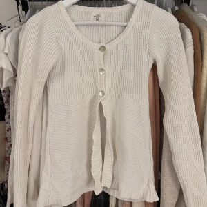 Vit stickad babydoll topp - Säljer en vit stickad babydoll kofta från L.O.G.G. med dekorativa knappar framtill. Stl xs, kontakta för fler bilder på. Har en fläck längst ned och vid etiketten. Vintage babydoll topp kom med rimlig prisförslag 
