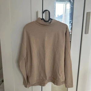 Beige polotröja från Gina Tricot - Säljer en stilren beige polotröja från Gina Tricot. Tröjan har långa ärmar och en mjuk polokrage, perfekt för kyligare dagar. Passar bra till både jeans och kjol.