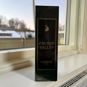 Orchid Valley från Laverne KSA - Orchid Valley från Laverne är en unisexparfym med en elegant grön flaska och svart kork. Doften har en rik blandning av vita blommor, citrus, träiga och myskiga toner, med inslag av puder, sötma, grönt, fruktigt, tvåligt och animaliskt. Perfekt för den som söker en mångsidig och sofistikerad doft.