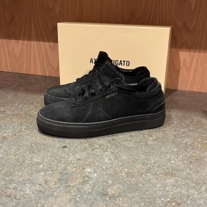 Svarta sneakers från Axel Arigato - Snygga svarta sneakers i mocka från Axel Arigato. Skorna har en stilren design med snörning och en diskret logga på sidan. Perfekta för en trendig look. Använda fåtal gånger så de är i super fint skick! Låda skickas med! 