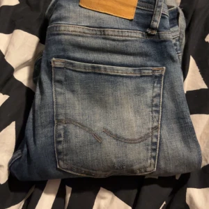 Jack and jones ripped jeans - Snygga blå slim fit jeans från Jack & Jones med slitna detaljer. Perfekta för en avslappnad stil. De har en klassisk femficksdesign och en bekväm passform.