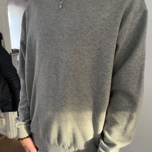 Grå tröja med dragkedja från ASOS DESIGN - Säljer en stilren grå tröja från ASOS DESIGN med halv dragkedja. Perfekt för en avslappnad look. Tröjan har långa ärmar och ribbade muddar vid ärmslut och nederkant. Tröjan är XS men passar S. Tröjan är knappt använd och säljs för att den är för liten. Hör av er vid funderingar!
