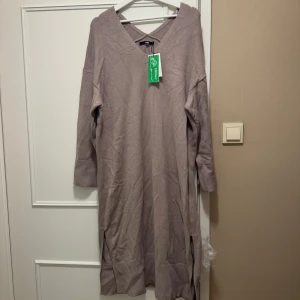 Beige långklänning från Bik Bok - Snygg beige långklänning från Bik Bok med v-ringning och långa ärmar. Klänningen har en ribbad kant och är perfekt för en stilren look. Den är i ett mjukt material som ger en bekväm passform. Slits i sidorna. Aldrig använt. 