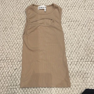 Beige ärmlös topp från Remain - Snygg beige ärmlös topp från Remain med en unik cut-out detalj vid bröstet. Storlek 34.