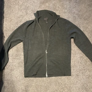 Grå full zip från H&M - Säljer en stilren grå kofta från H&M i regular fit. Koftan har en praktisk dragkedja framtill och långa ärmar. Perfekt för lager-på-lager under kyligare dagar.