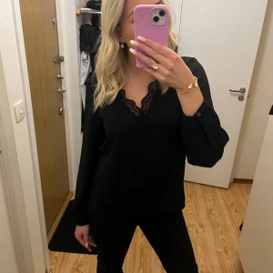 Svart spets blus - Säljer en svart blus med spets i v-ringningen från Veramoda, helt ny och aldrig använd. Även lite öppen i ryggen.