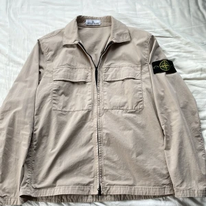 Beige overshirt från Stone Island - Säljer en beige overshirt från Stone Island i storlek S. Skick 9/10, nästan aldrig använd. Ingår kvitto och påse från Stone Island. Köpt för 4300 kr, mitt pris 2700 kr. För mer frågor och bilder hör av er! 