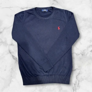 Ralph Lauren tröja - mörkblå tröja från Ralph Lauren. EJ SMUTS SOM SYNS PÅ FÖRSTA BILDEN!! Det var lite vatten som kom på armen! Tröjan har långa ärmar och ribbade muddar vid ärmslut och nederkant. Perfekt för en avslappnad men ändå elegant look.