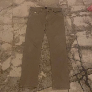 Gråa byxor från Hugo Boss - Snygga gråa  byxor från Hugo Boss med klassisk design. Byxorna har en rak passform och är tillverkade i ett bekvämt material. Perfekta för en stilren look, de är aldrig använda och köptes för 1500kr.